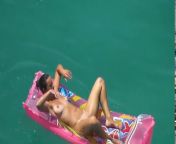 Голая девушка лежит в воде на надувном матрасе